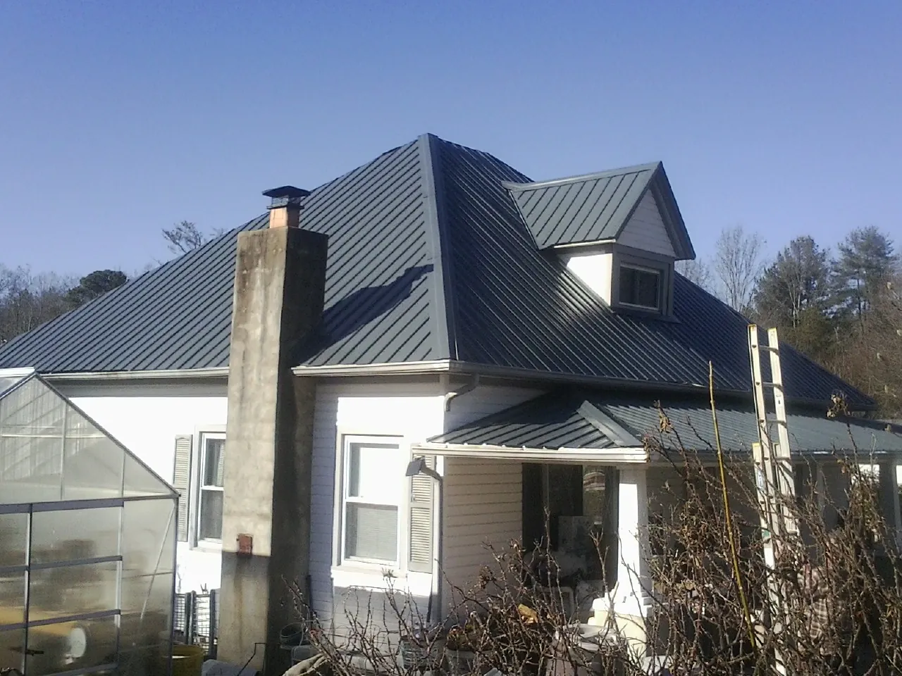 Dark blue standing seam metal roof on a white farmhouse with dormer — Slate & Tile Roof Repair by Roofing Brothers in Shandaken