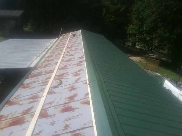 Old rusted panels beside newly installed green metal roofing — Wind Damage Roof Repair by Roofing Brothers in Shandaken