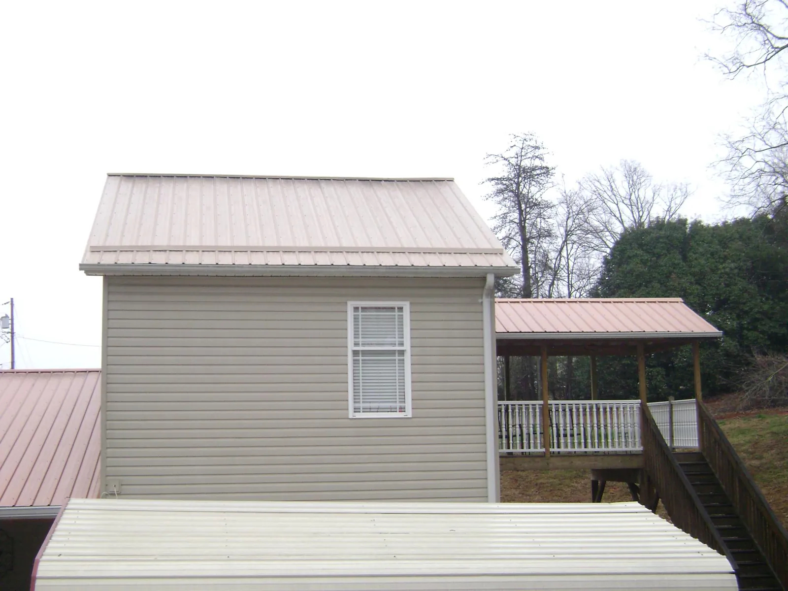 Tan metal roofs on a two story addition and attached porch, from a Roof Replacement job in Shandaken