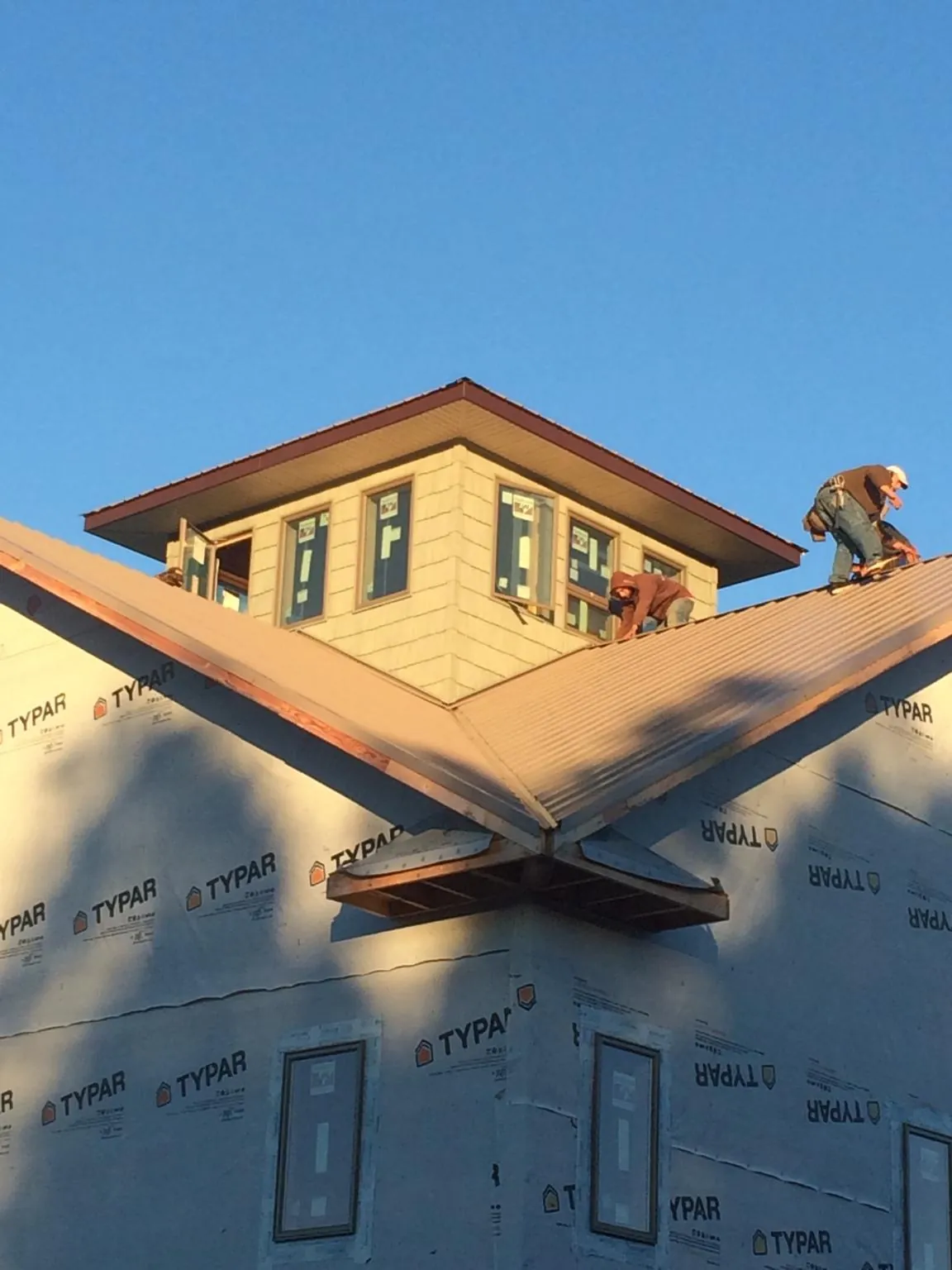 Roofers working around a rooftop cupola on a new metal roof at sunset — Roof Waterproofing in Shandaken by Roofing Brothers